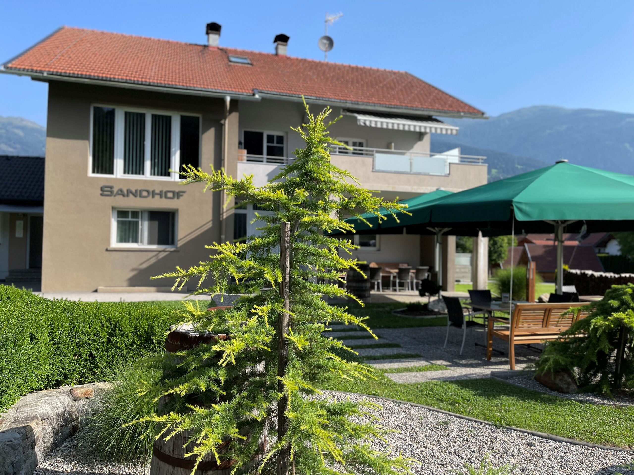 Hauptgebäude der Radlerstation Sandhof mit Garten und Bergpanorama